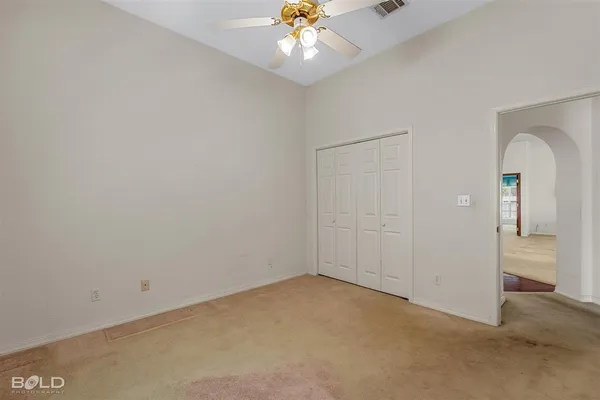 an empty room with closet and a chandelier fan