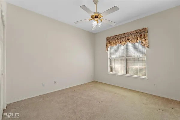 an empty room with windows and chandelier fan