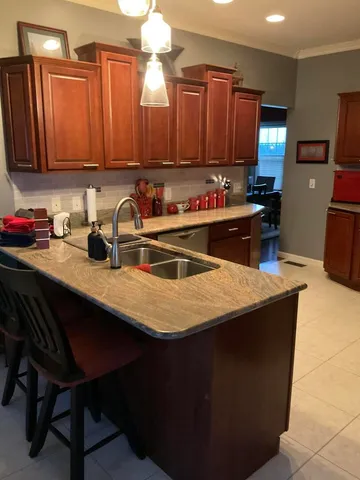 a kitchen with kitchen island granite countertop a sink a stove and cabinets