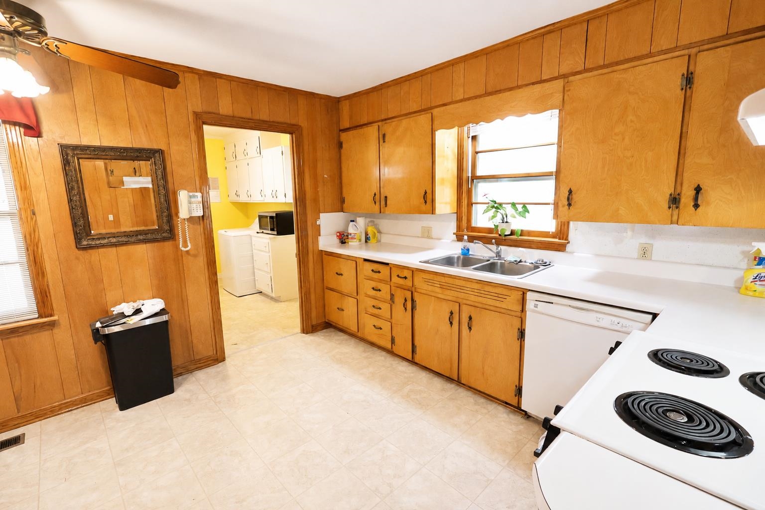 2000 Culbreath Road Covington, TN 38019 - Photo 2 of 16 Kitchen featuring wood-paneled walls, light-colored flooring, wood cabinetry, white countertops, and white appliances