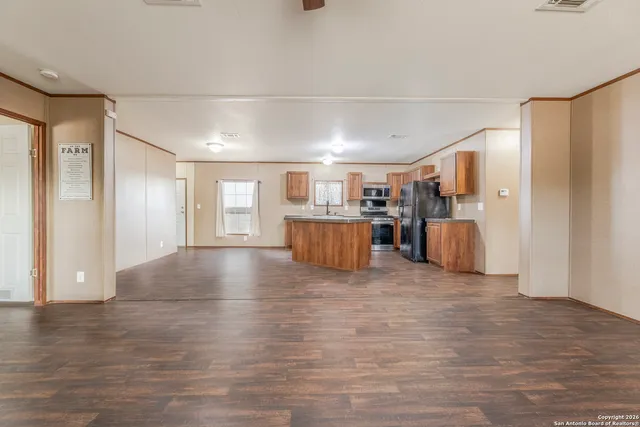 a view of a electric appliances in kitchen and empty room with wooden floor