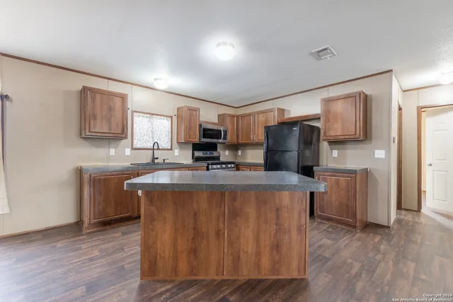 a kitchen with kitchen island wooden cabinets a refrigerator sink and stove