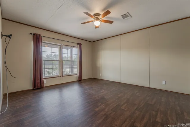 a view of an empty room with window and wooden floor