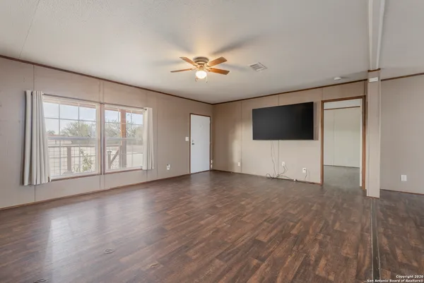 a view of an empty room with a window and wooden floor