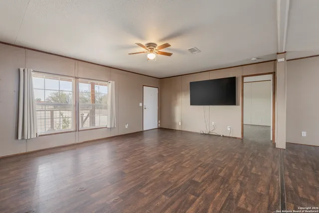 a view of an empty room with a window and wooden floor
