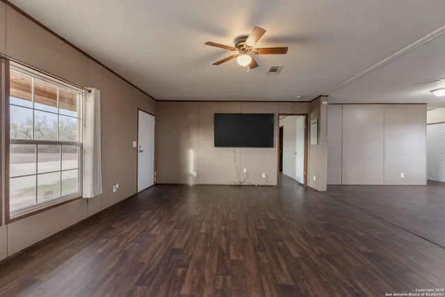 a view of empty room with wooden floor and fan