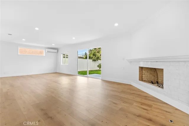 a view of empty room with wooden floor and kitchen