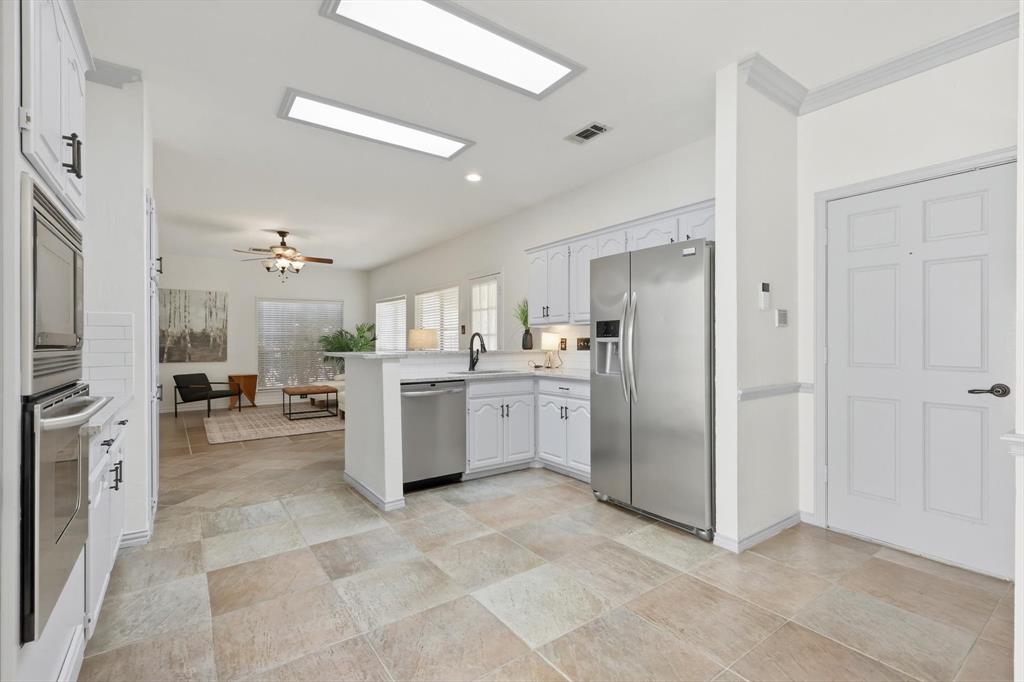 4350 Timberglen Road Dallas, TX 75287 - Photo 11 of 33 Kitchen featuring stainless steel appliances, a peninsula, a ceiling fan, and white cabinets