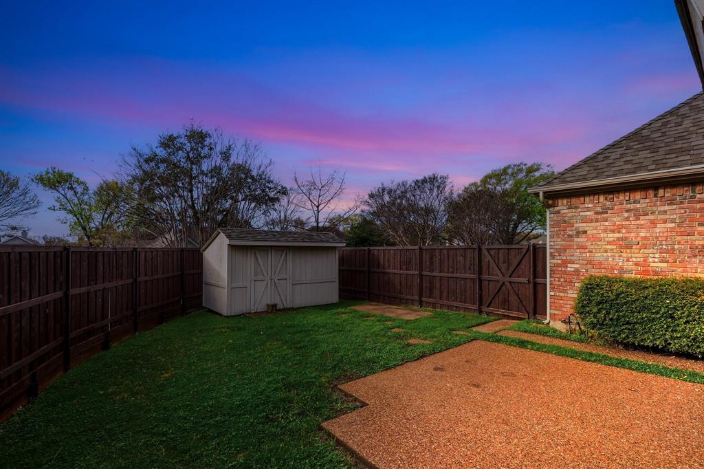 4350 Timberglen Road Dallas, TX 75287 - Photo 31 of 33 Yard at dusk with a storage unit and a fenced backyard