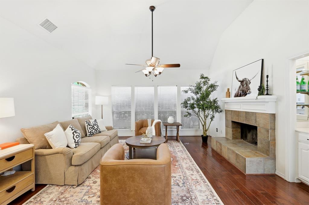4350 Timberglen Road Dallas, TX 75287 - Photo 4 of 33 Living room featuring a ceiling fan, vaulted ceiling, dark wood-style flooring, and a fireplace