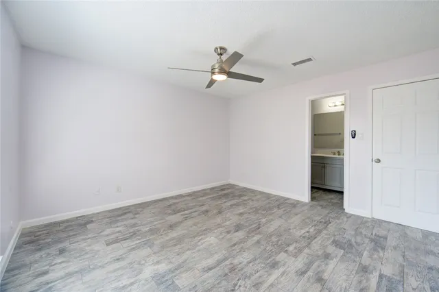 an empty room with wooden floor ceiling fan and windows