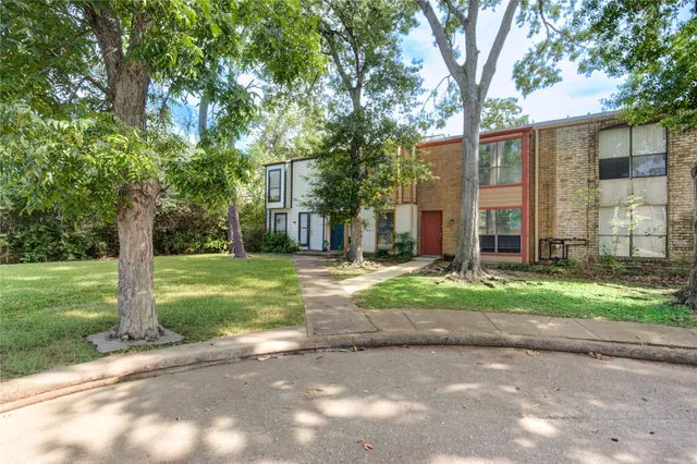 a view of a house with a yard and large tree