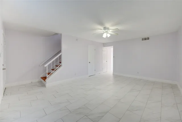 an empty room with a ceiling fan and carpet