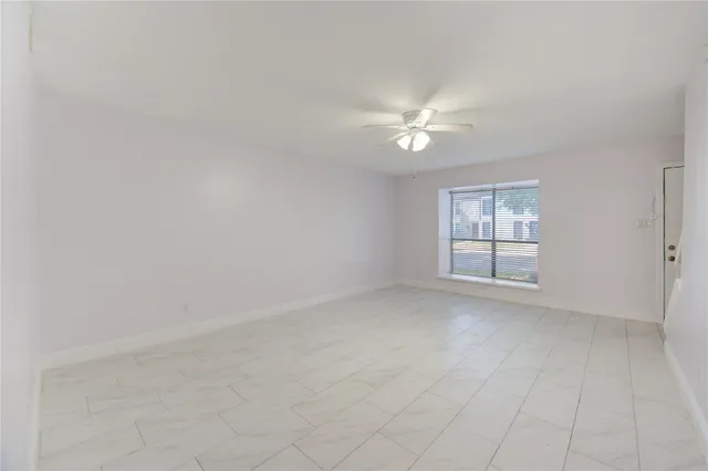 an empty room with windows and fan