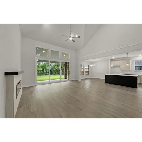 a living room with wooden floor and kitchen view