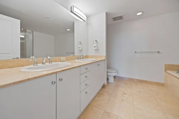 a spacious bathroom with a granite countertop sink a toilet and a mirror