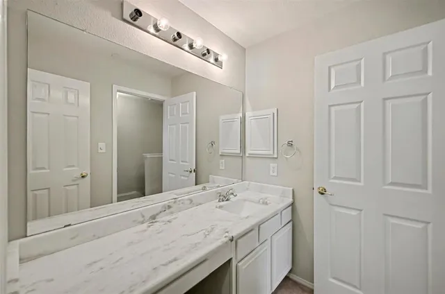 a bathroom with a granite countertop double vanity sink and mirror