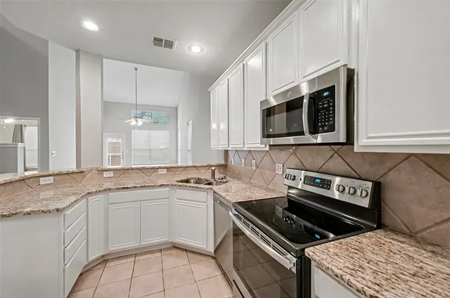 a kitchen with granite countertop a stove sink and microwave