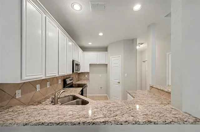 a kitchen with granite countertop a refrigerator and a sink