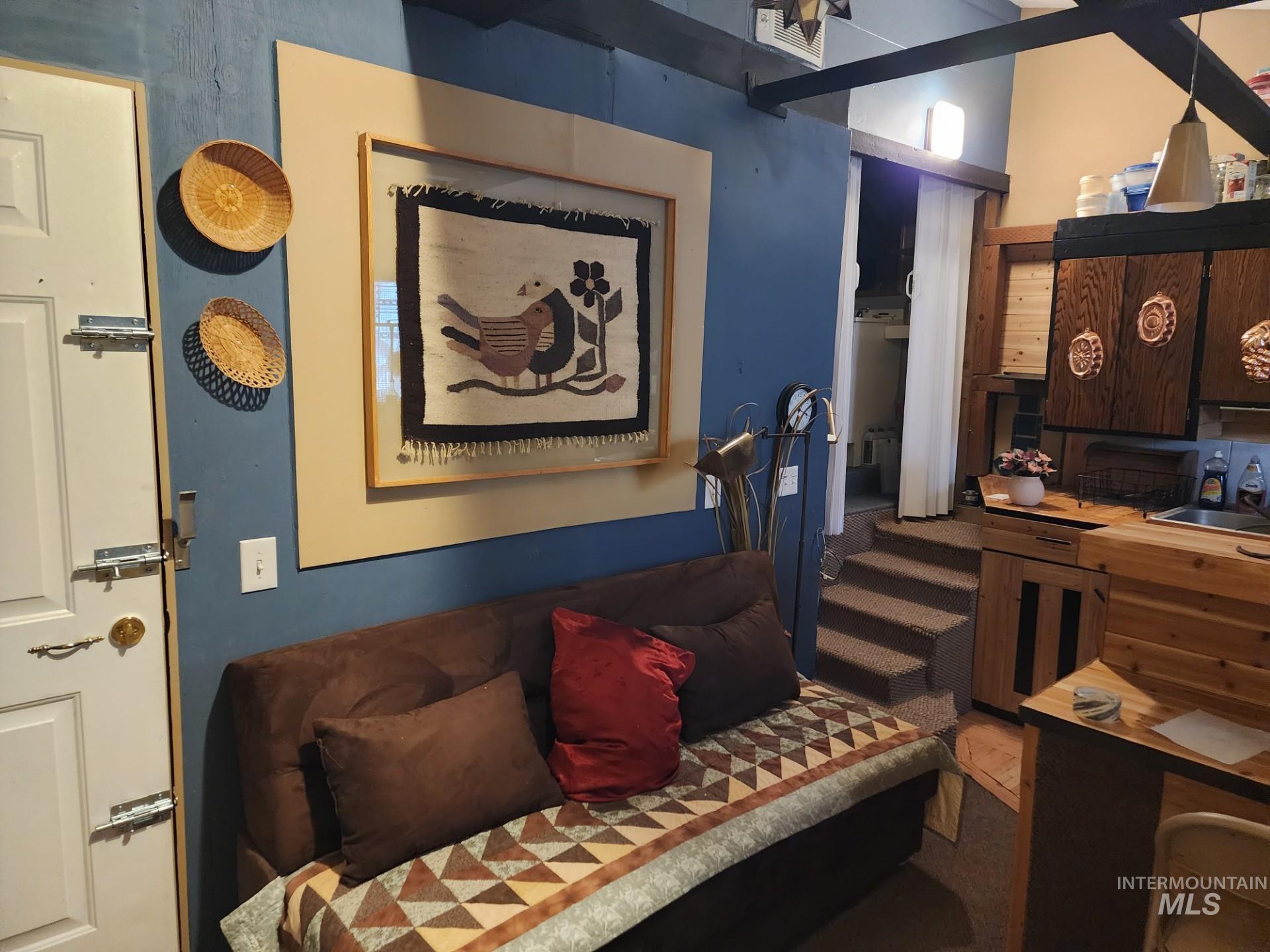 235 5th Street Grand View, ID 83624 - Photo 11 of 22 Compact living area featuring a wood-finish door, blue accent wall, exposed ceiling beams, built-in shelving, and a multi-level design