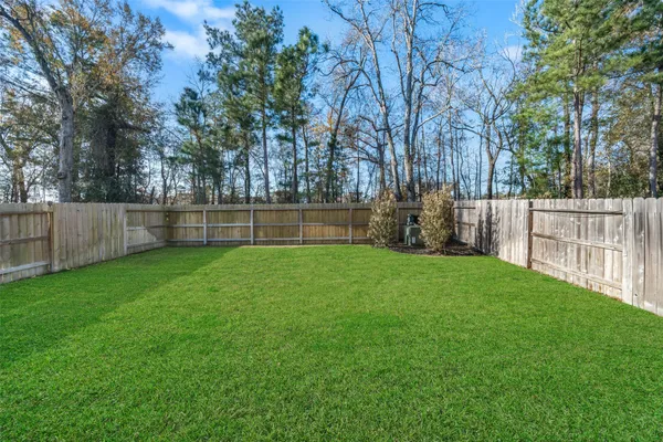 a view of a backyard with wooden fence and large trees