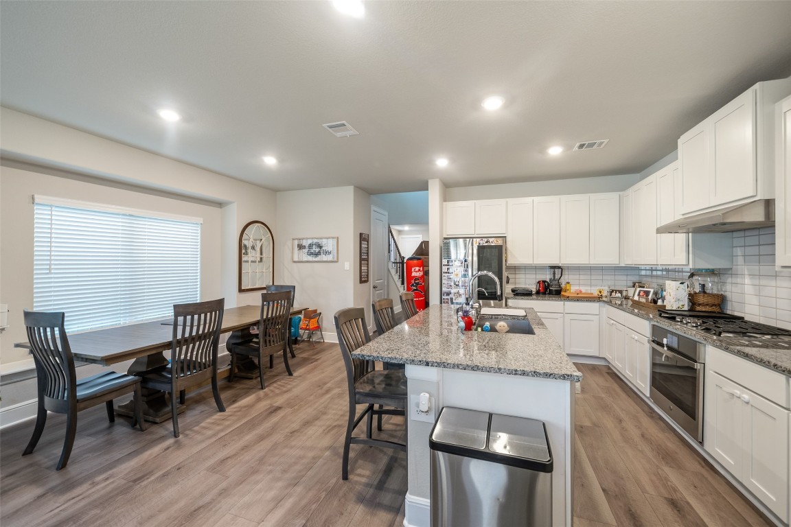 27479 Vivace Drive Spring, TX 77386 - Photo 5 of 25 a kitchen with stainless steel appliances granite countertop a stove top oven a sink dishwasher a dining table and chairs with wooden floor