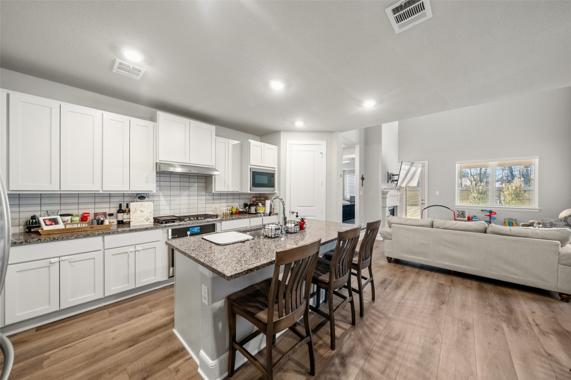 27479 Vivace Drive Spring, TX 77386 - Photo 7 of 25 a kitchen with stainless steel appliances kitchen island granite countertop a stove a sink a refrigerator and white cabinets with wooden floor