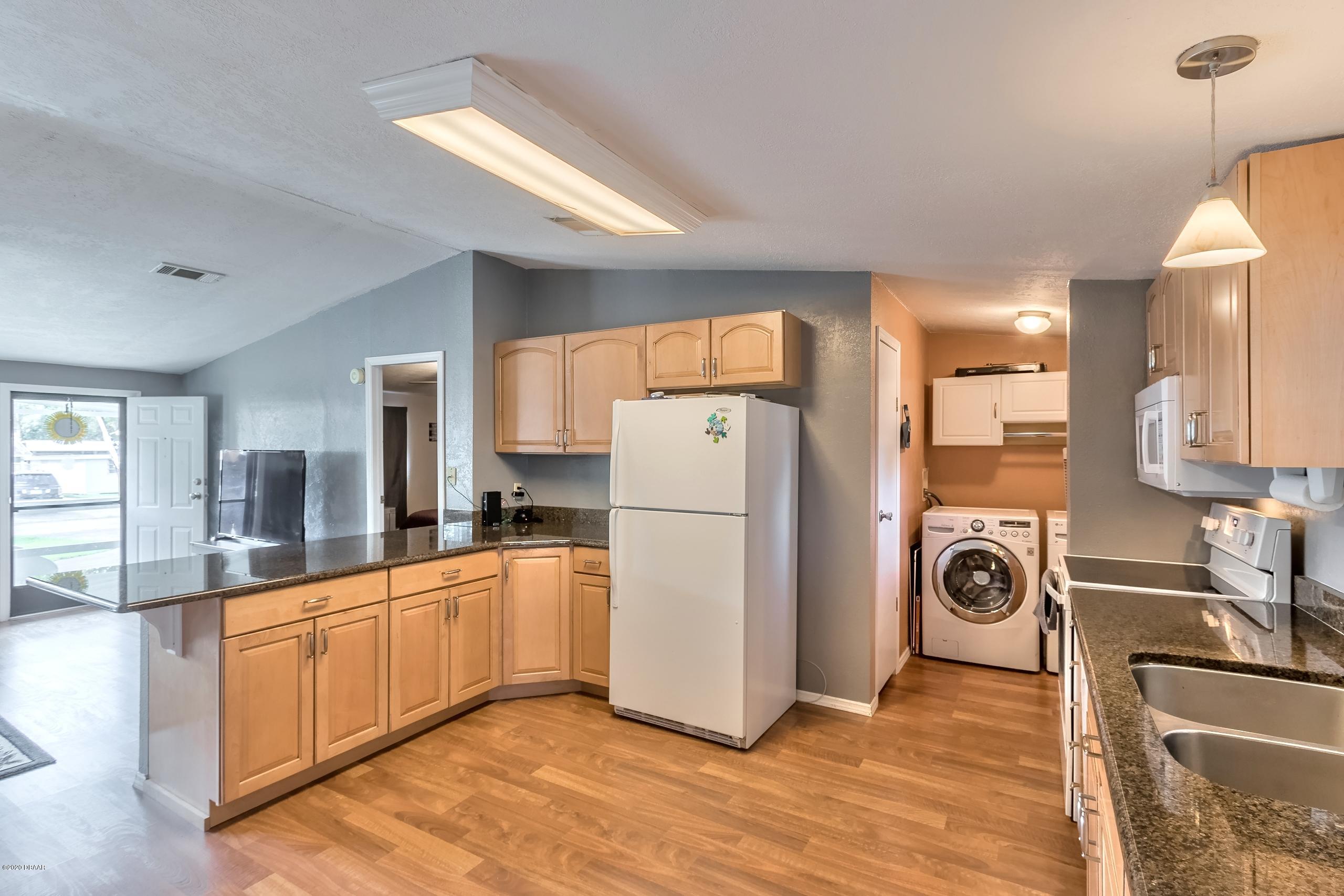 24513 Snail Road Astor, FL 32102 - Photo 14 of 40 a kitchen with a refrigerator a stove top oven a sink and cabinets