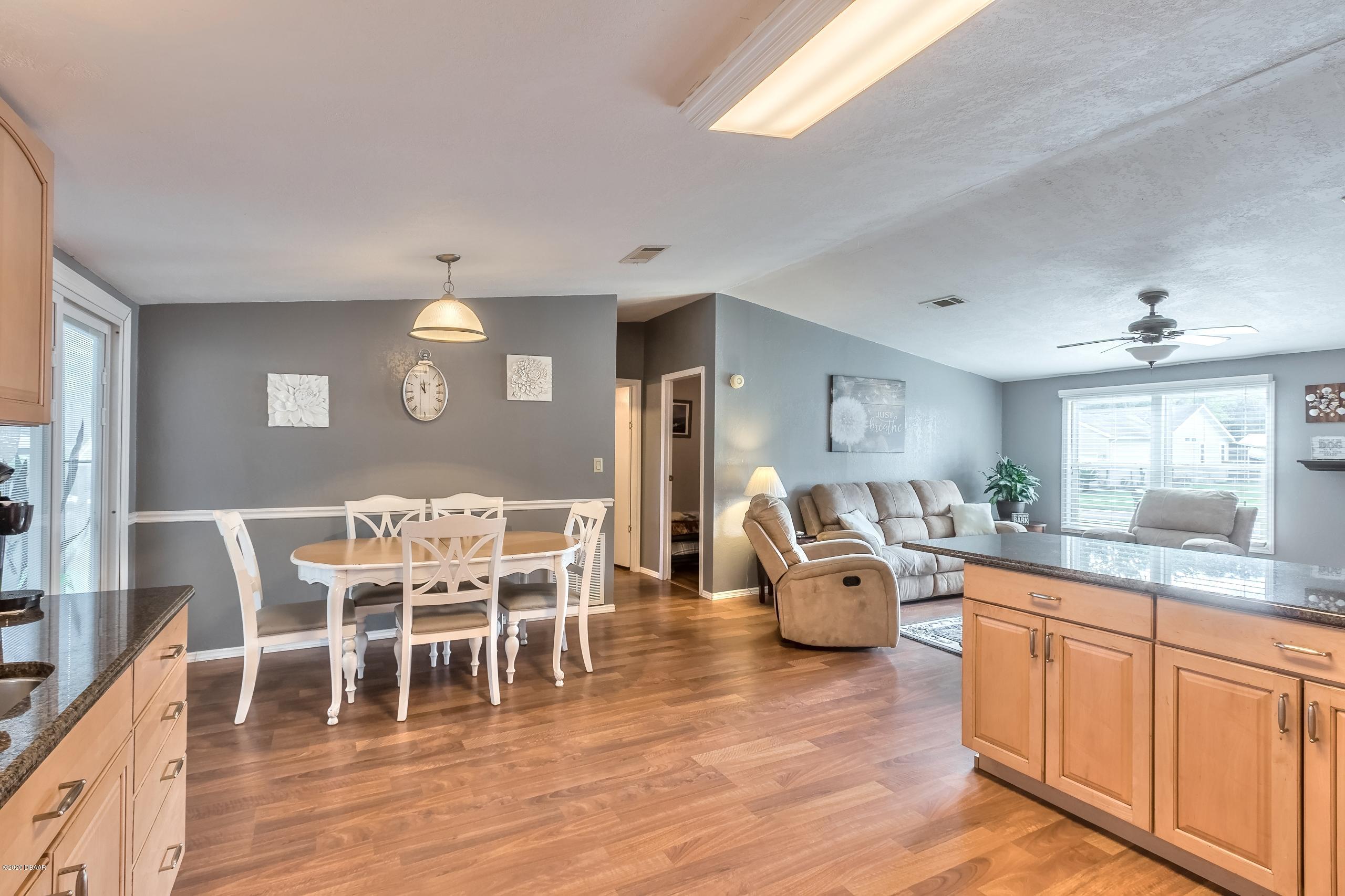 24513 Snail Road Astor, FL 32102 - Photo 15 of 40 a dining room with wooden floor a chandelier a glass table and chairs