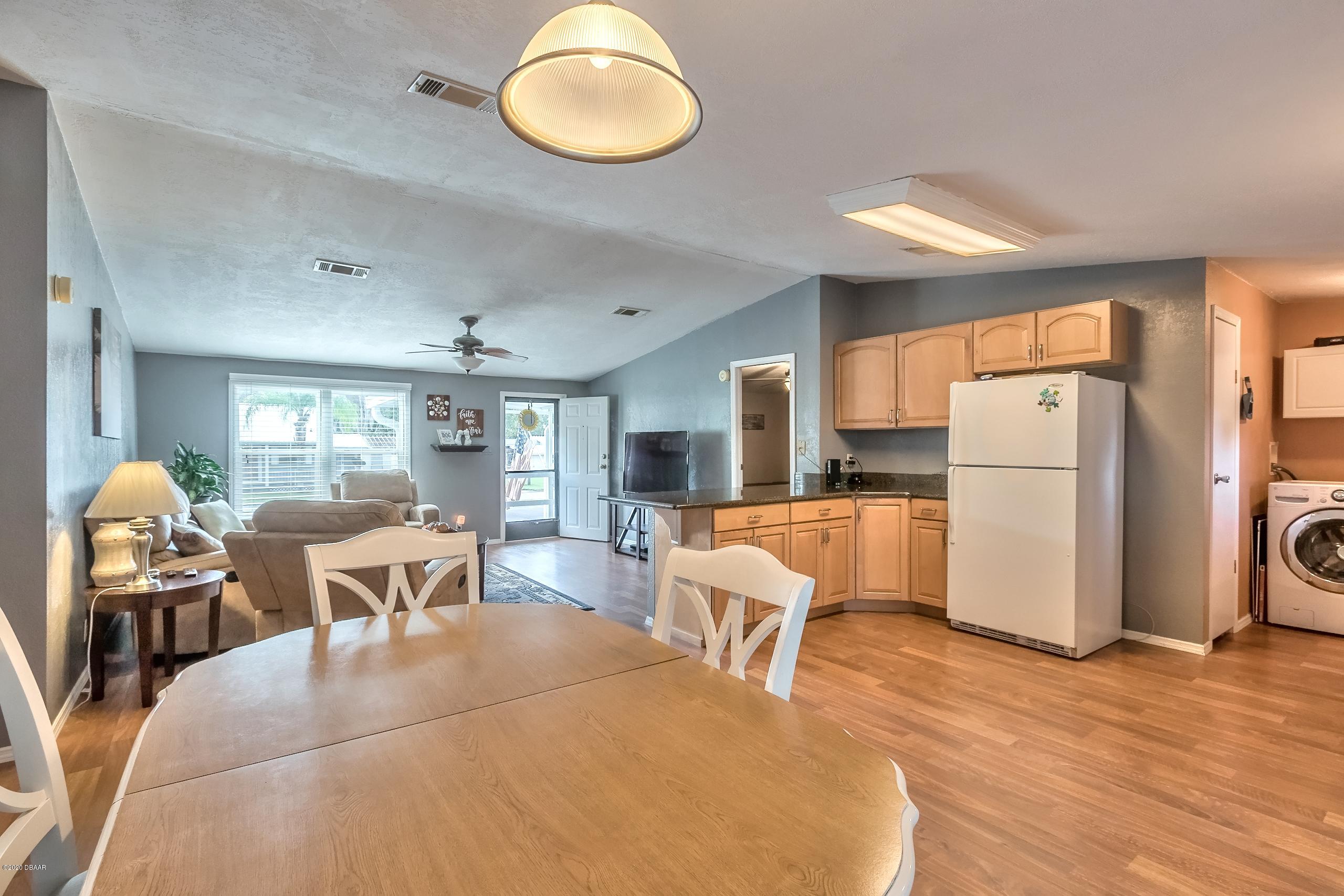 24513 Snail Road Astor, FL 32102 - Photo 17 of 40 a living room with furniture a refrigerator and dining table