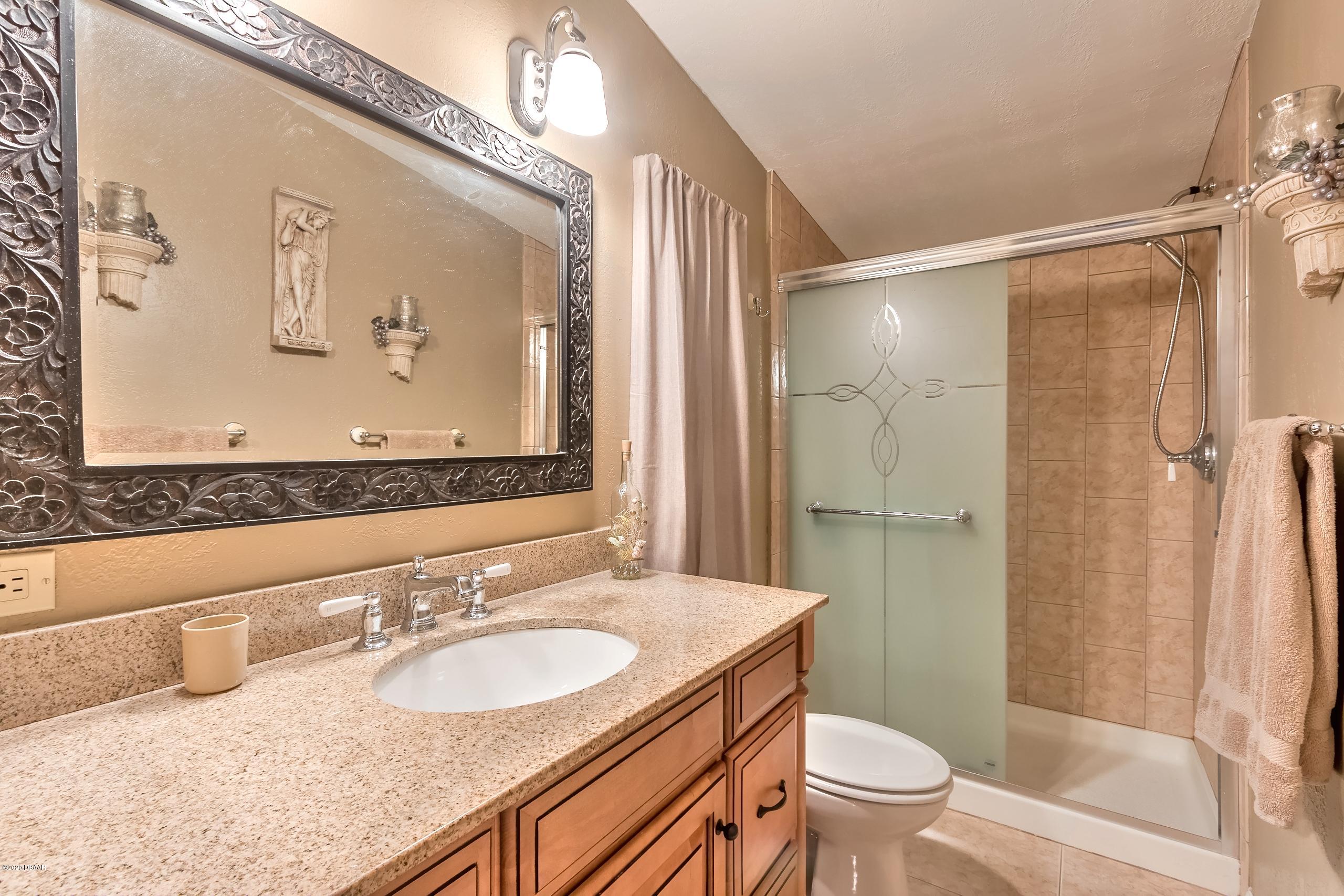 24513 Snail Road Astor, FL 32102 - Photo 7 of 40 a bathroom with a granite countertop sink toilet and shower