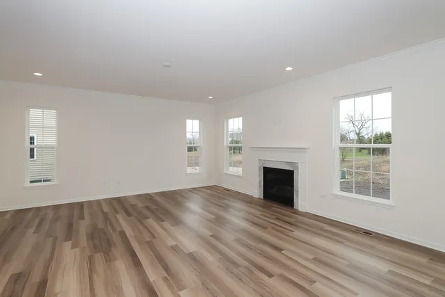 an empty room with wooden floor fireplace and windows