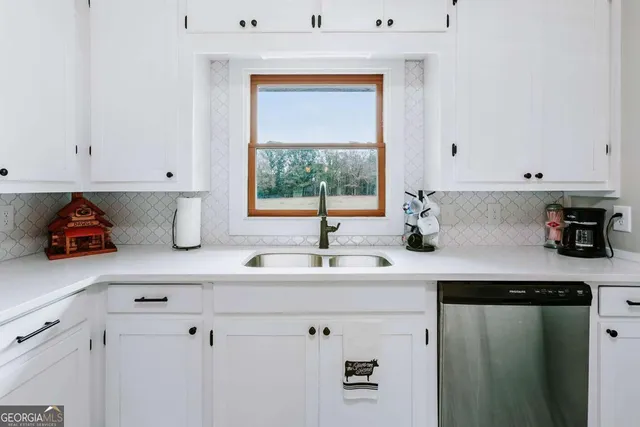 a kitchen with stainless steel appliances a sink dishwasher and white cabinets