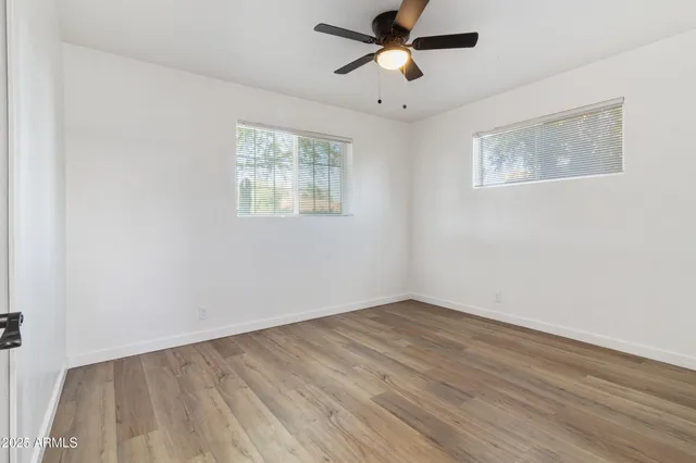 a view of empty room with wooden floor and fan