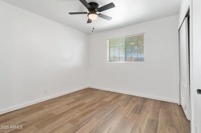 an empty room with wooden floor and ceiling fan