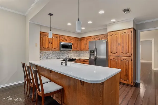 a kitchen with stainless steel appliances granite countertop a refrigerator a sink a stove a dining table and chairs