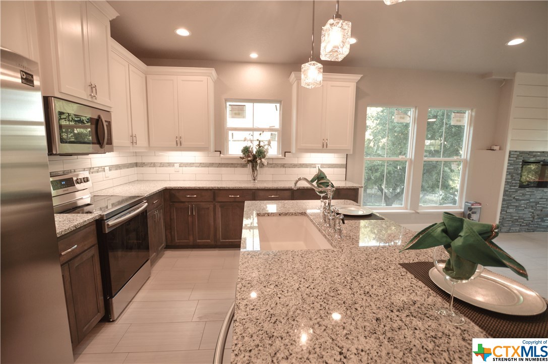 a large kitchen with lots of counter top space a sink stainless steel appliances and cabinets