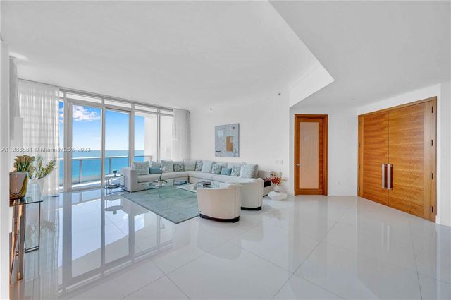 a living room with furniture and floor to ceiling windows
