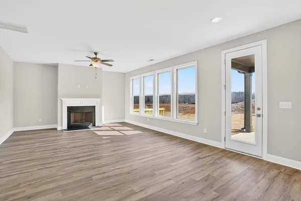 a view of an empty room with wooden floor fireplace and a window