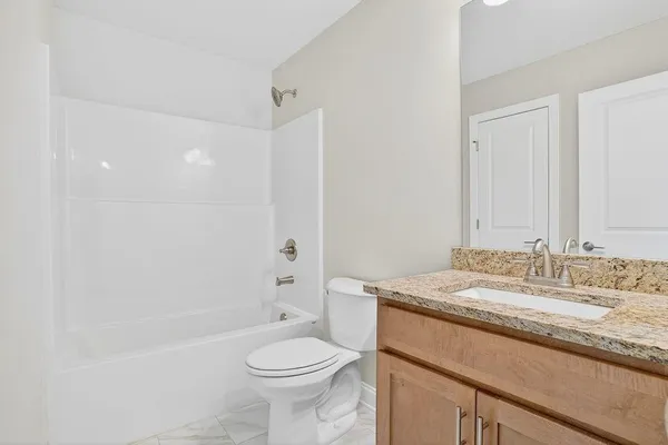 a bathroom with a granite countertop sink a toilet and shower
