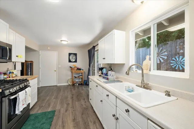 a kitchen with white cabinets and wooden floor