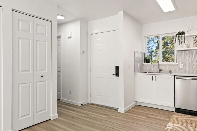 a view of a kitchen from the hallway with wooden floor and a living room