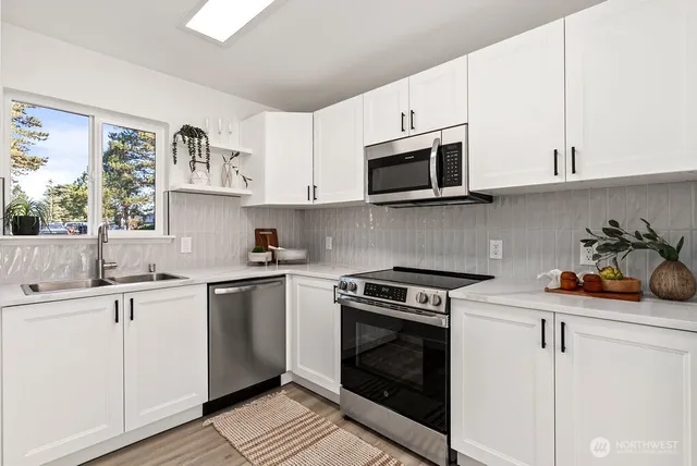 a kitchen with cabinets stainless steel appliances a sink and a stove