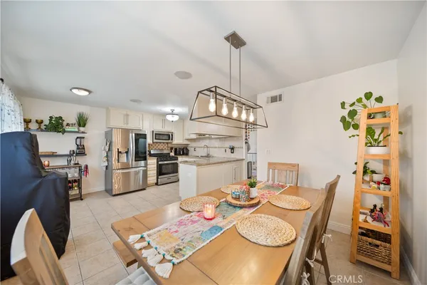 a kitchen with stainless steel appliances kitchen island granite countertop a table chairs and a refrigerator