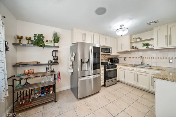a kitchen with stainless steel appliances granite countertop a refrigerator and a stove top oven