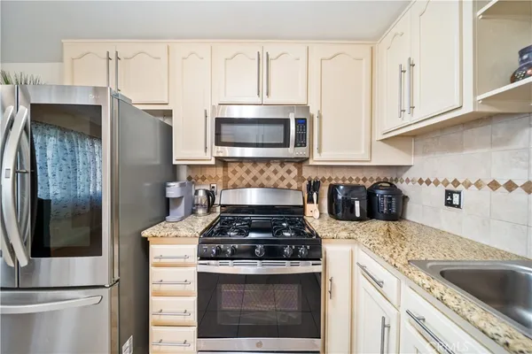 a kitchen with stainless steel appliances granite countertop a refrigerator stove and sink
