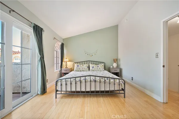 a bedroom with a bed a mirror and a window with wooden floor