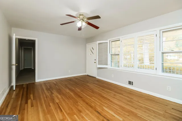 a view of an empty room with wooden floor and a window