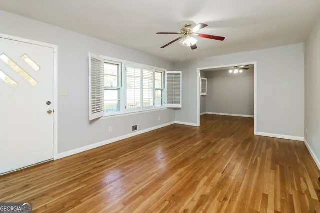 a view of empty room with wooden floor and fan