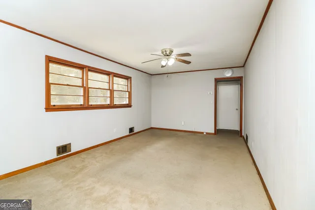 an empty room with windows and chandelier fan